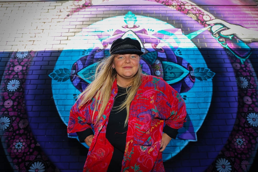 Young woman in front of mural.