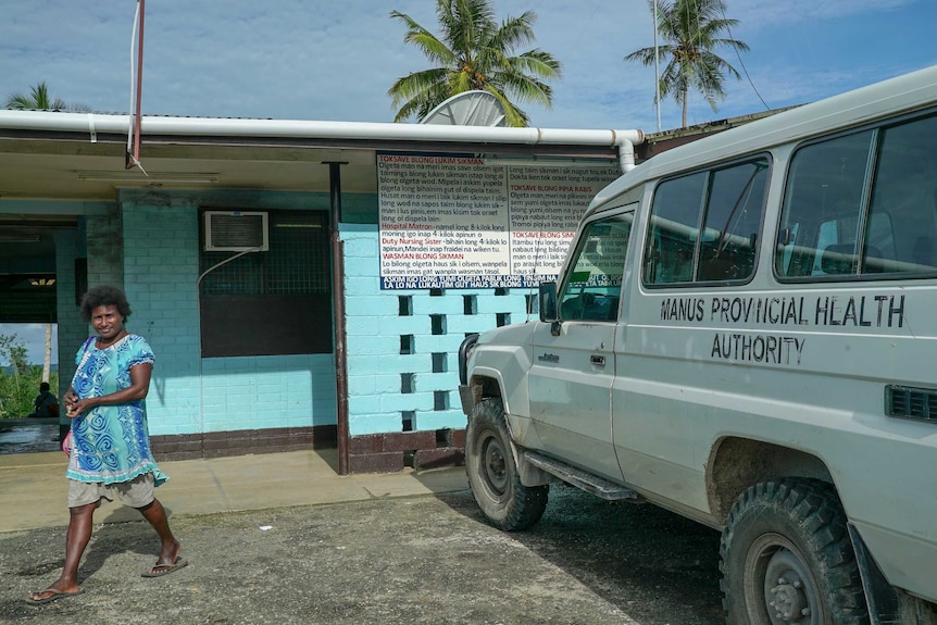 A Papua New Guinean woman walks out of a bright blue building