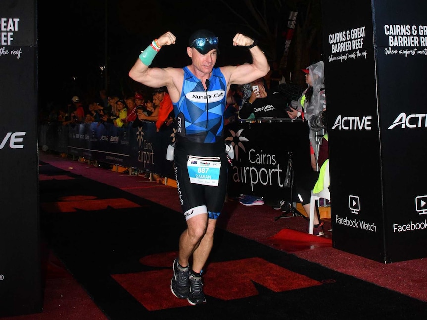 Damian Wood crosses the finish line in a triathlon, pictured in a story about budgeting for fitness