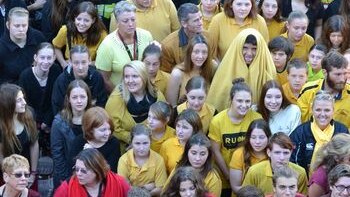 Students  in red, yellow and black clothes group to represent the Aboriginal Flag, at Taree High School.