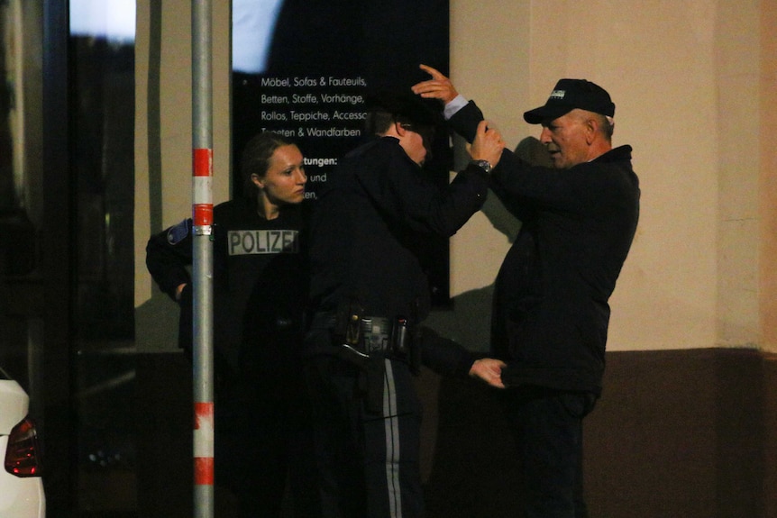 Police officers search a pedestrian following gunfire near a synagogue in Vienna.