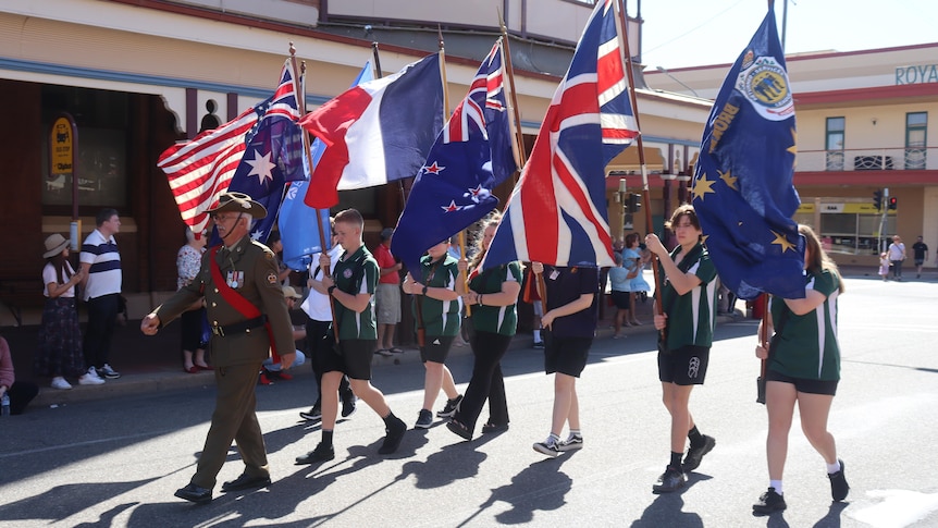 A group of students marching being led by a veteran 