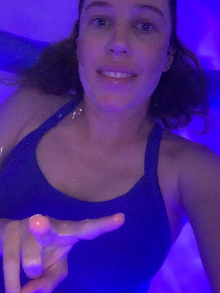 A woman in blue bathers in a blue-lit flotation tank. For a story on sensory deprivation therapy. 
