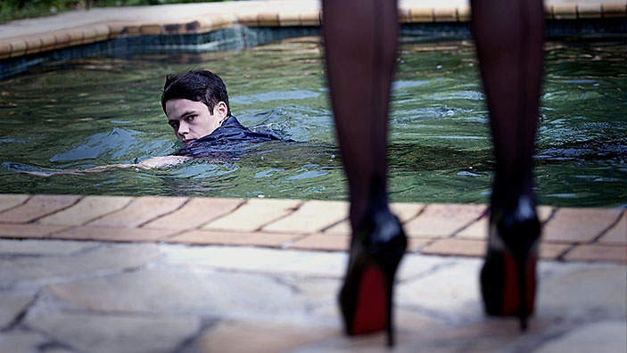 Leading actress Emmanuelle Béart plays a dominatrix, and is seated beside actor Harrison Gilbertson on a leather couch.