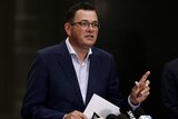 Premier Daniel Andrews speaks in front of a dark backdrop at a press conference