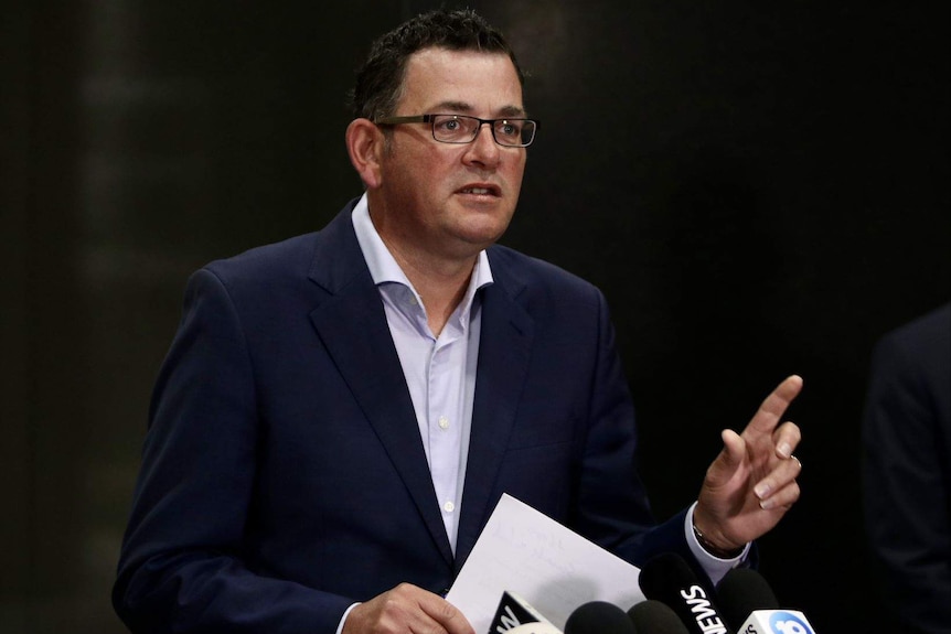 Premier Daniel Andrews speaks in front of a dark backdrop at a press conference