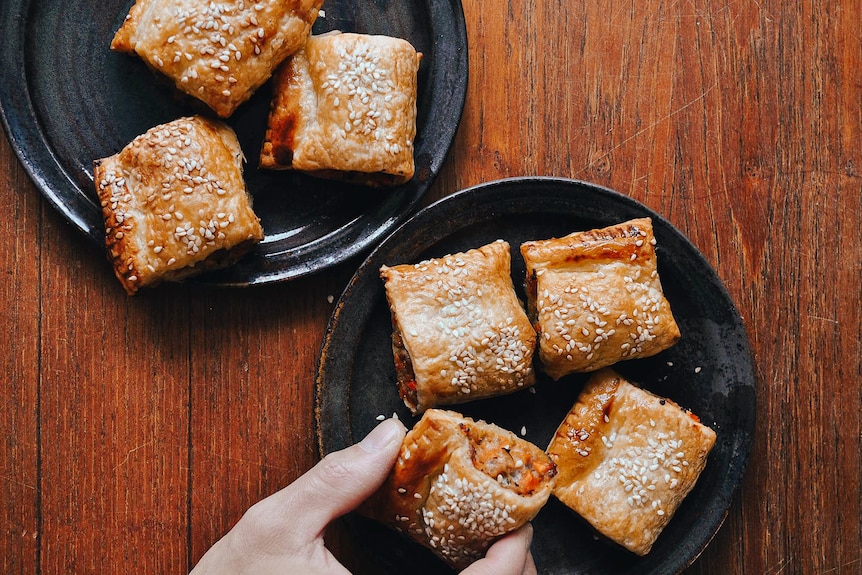 Two plates of bite-sized chicken and vegetable sausage rolls topped with sesame seeds, a fun family dinner.