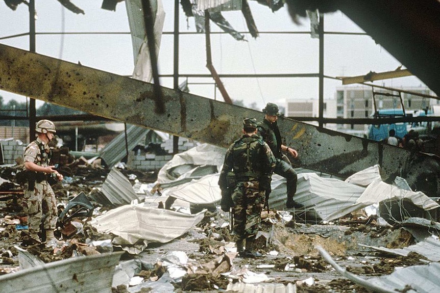 Three soldiers inspect rubble following an airstrike on an Iraqi building.