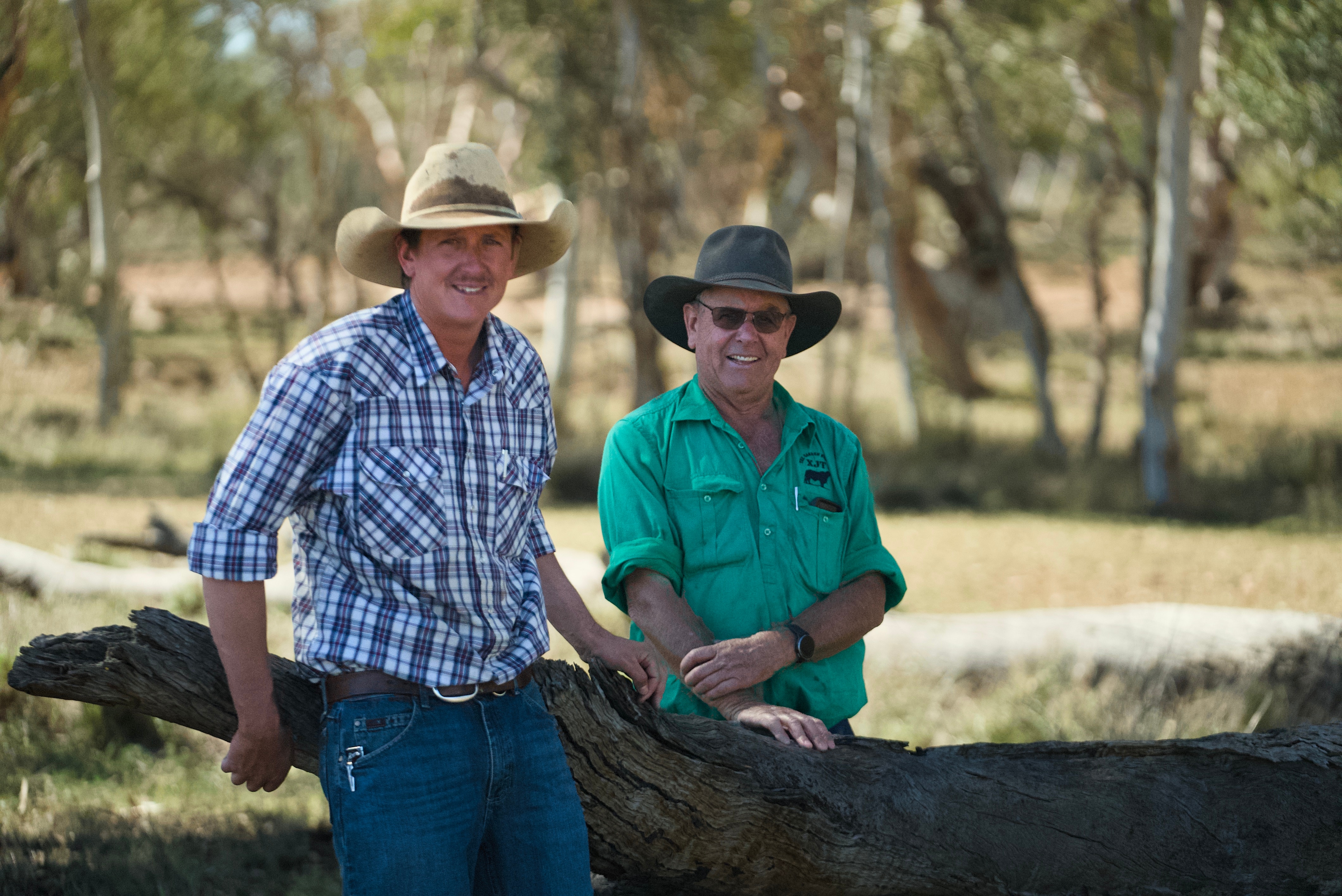 Dos hombres con sombreros se encuentran junto a una sucursal en un entorno rural.
