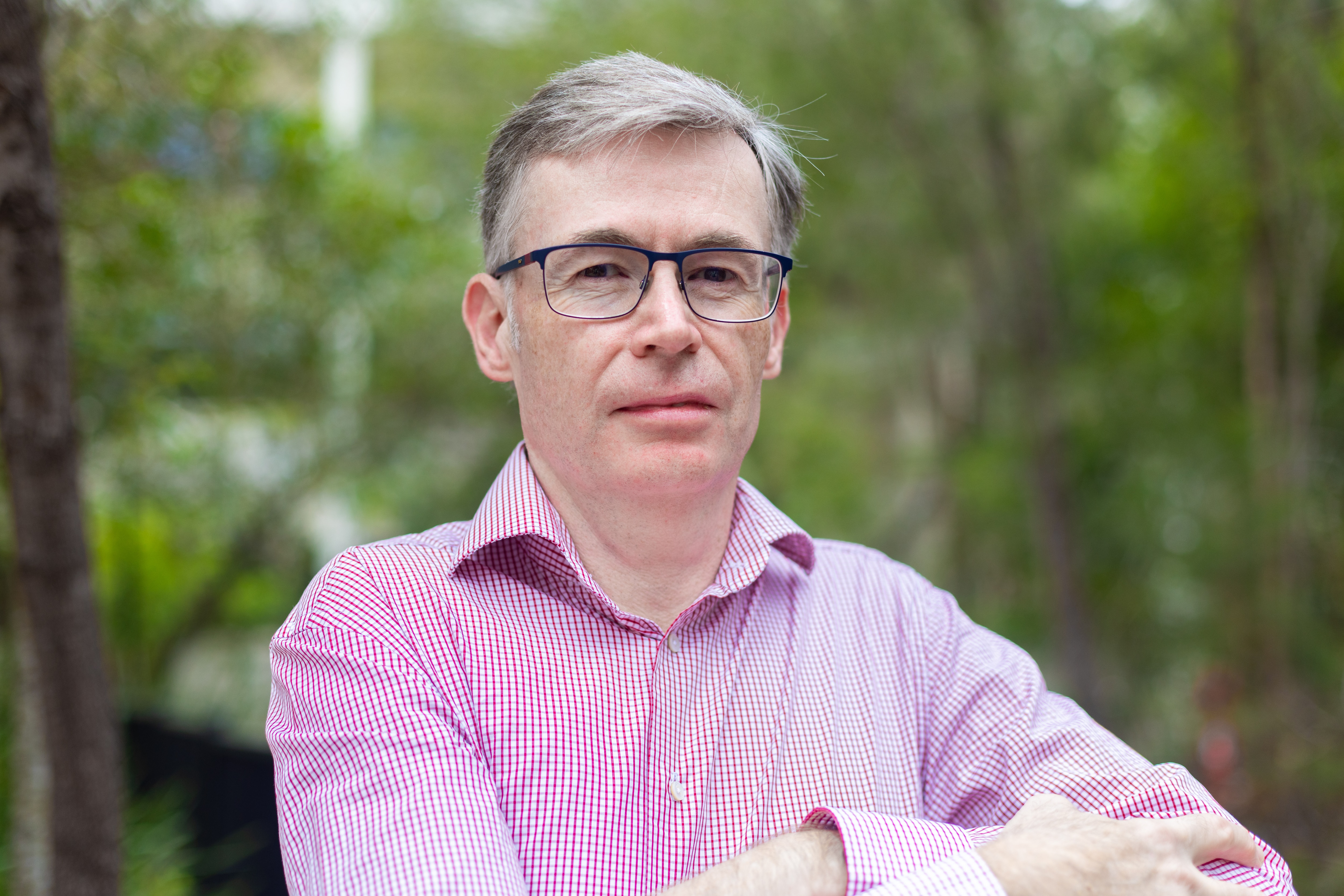 Um homem de camisa rosa posando para uma foto.