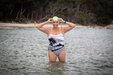 Caitlyn Feldmann in swimsuit and cap in the water, pictured in a story about budgeting for fitness