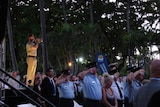 Crowds stand silent as soldier plays the Last Post at Anzac Day dawn service in Townsville.
