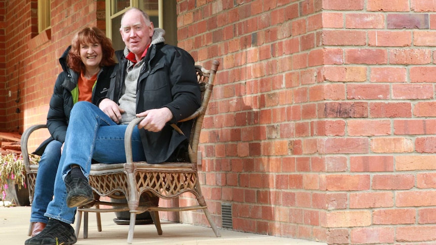 woman and man sit together on chair in front porch