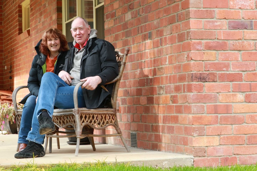woman and man sit together on chair in front porch
