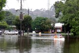Two men canoe through a flooded street in Warragul