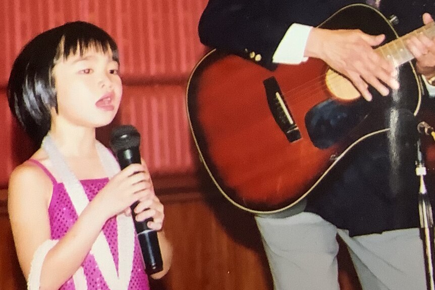 一个小女孩在舞台上唱歌。