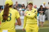 Australian cricketer Jess Jonassen stands on the ground throwing a ball to her teammate prior to a game.