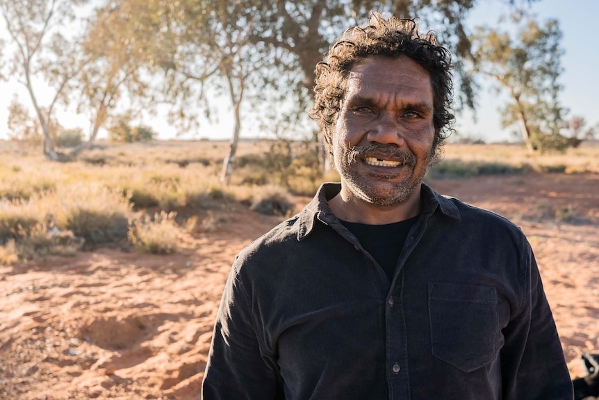 Artist Vincent Namatjira smiles at the camera, in his community of Indulkana on the APY Lands in remote SA 