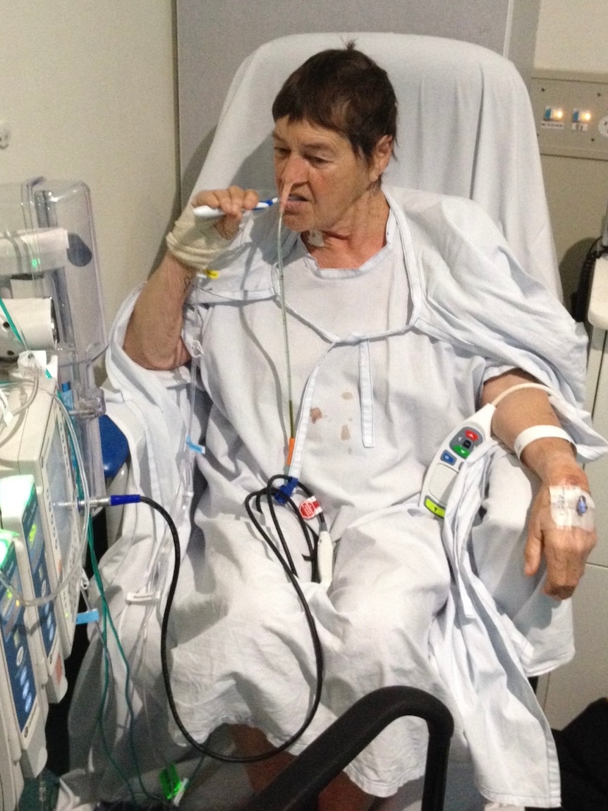 A woman in a hospital gown surrounded by machines.