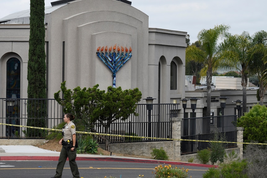 A police officer walks past a synagogue decorated with a menorah. it is cordoned off with police tape.