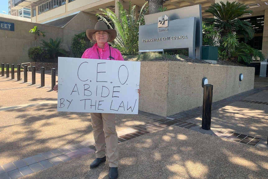 Woman holding sign that reads "c.e.o abide by the law".