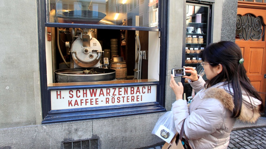 A tourist takes a picture through the open window of H. Schwarzenbach coffee roastery in Zurich.