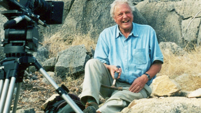 Sir David Attenborough sits on a rock at the Riversleigh fossil site.