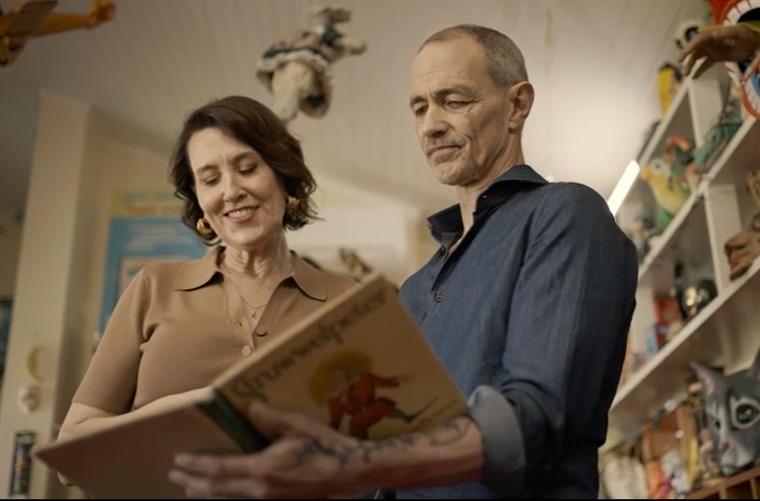 Andy Griffiths holds an old picture book open, showing it to Virginia Trioli