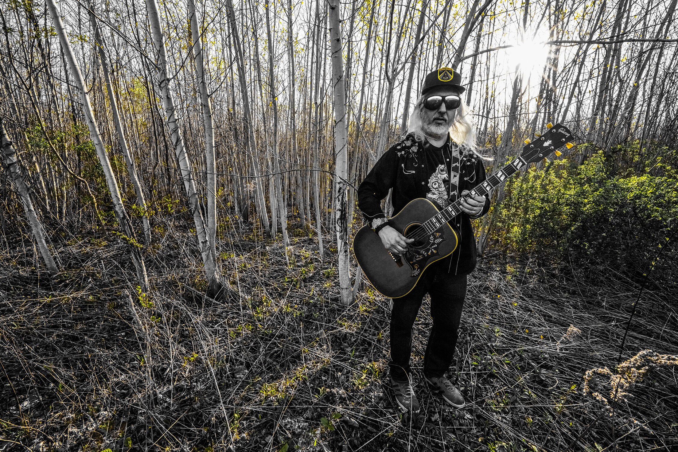 Dinosaur Jr. frontman and solo artist DJ Mascis stands in a forest clearing during daybreak