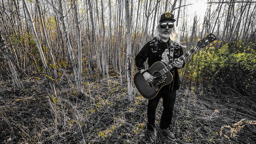 Dinosaur Jr. frontman and solo artist DJ Mascis stands in a forest clearing during daybreak