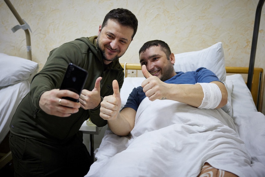 Ukraine's President Volodymyr Zelenskyy poses for a selfie with an injured soldier in a hospital.