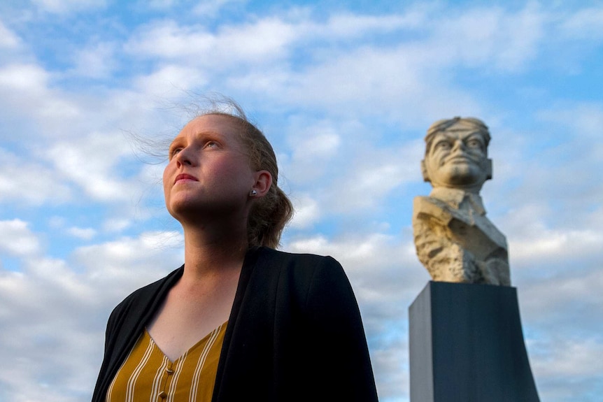Woman stands near statue of Bert Hinkler.