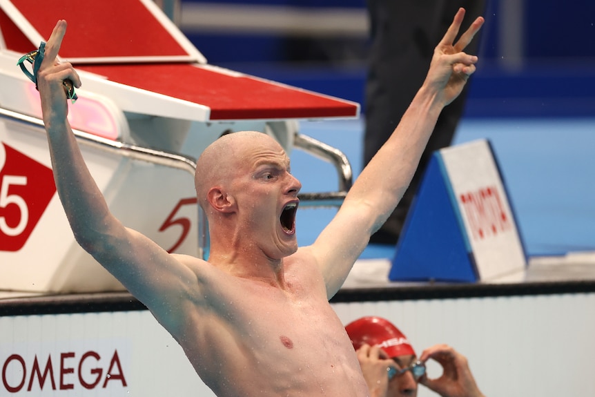 El nadador celebra en la piscina gritando con las manos en el aire. 