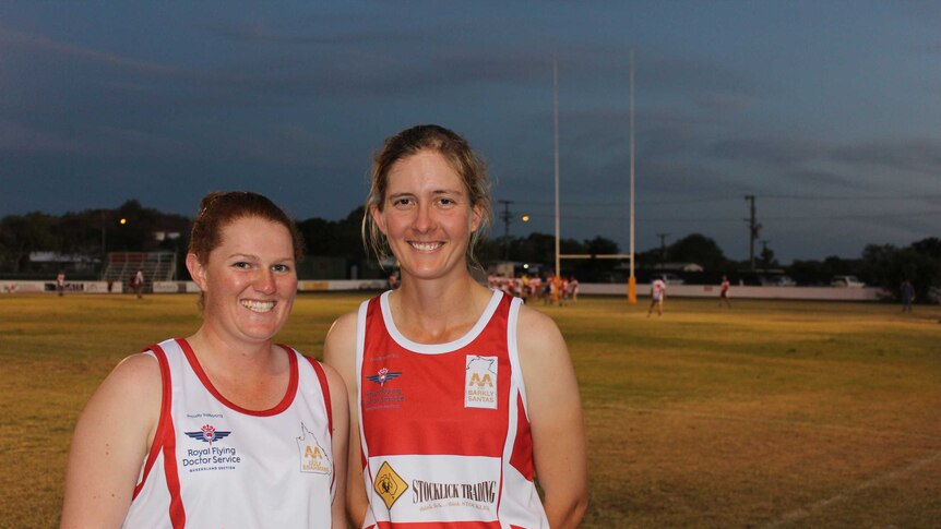 Touch football players Gemma White and Mary Vaughan stand together in front of a football field in Mount Isa.