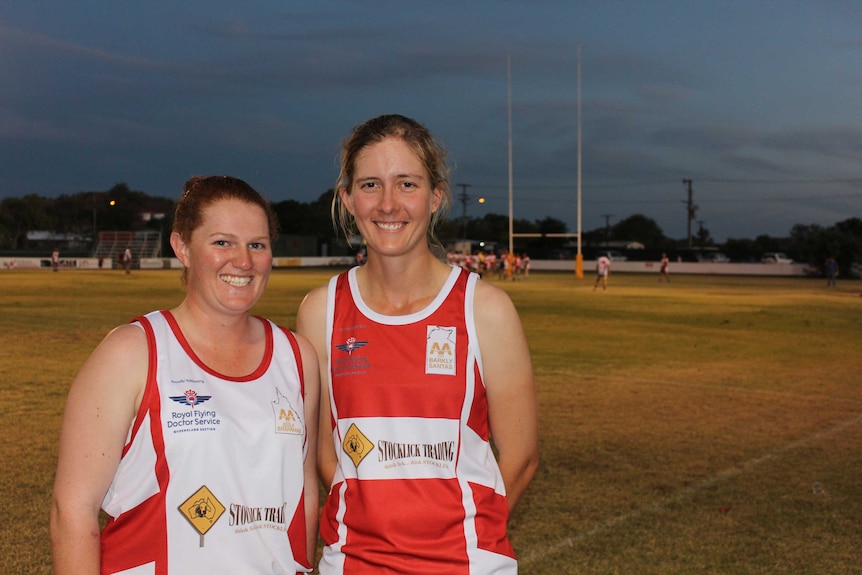 Touch football players Gemma White and Mary Vaughan stand together in front of a football field in Mount Isa.