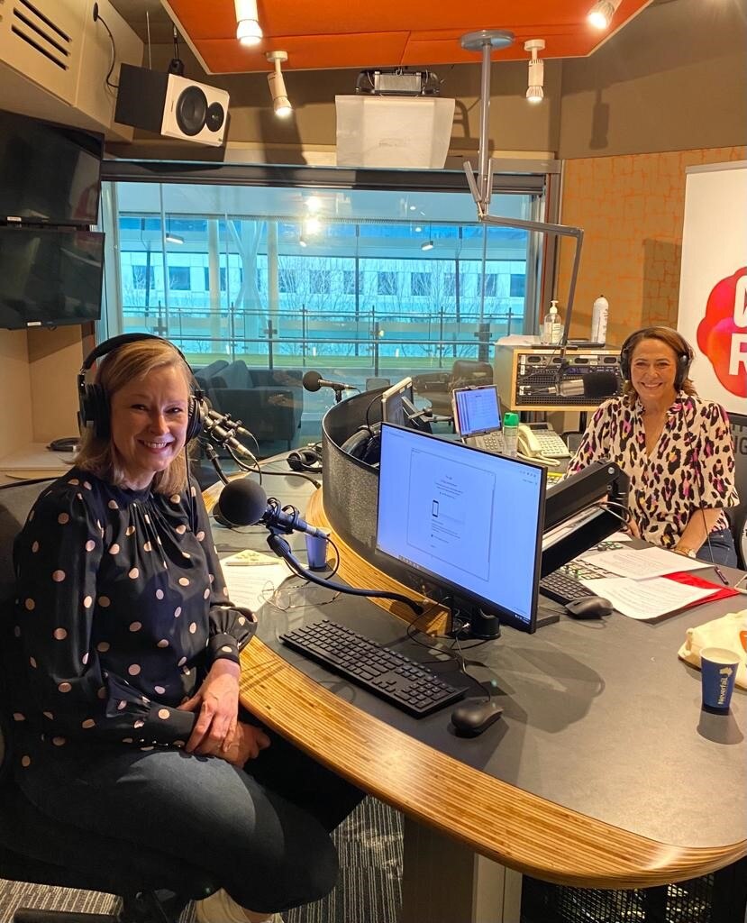 Two women wearing headphones in a radio studio.
