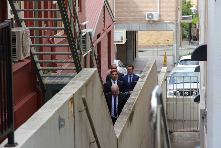 Four men walking down an alley