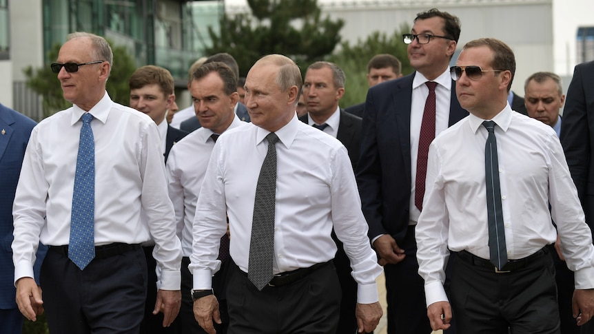A group of men in white business shirts and long ties walk together