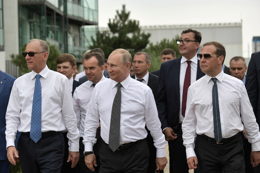 A group of men in white business shirts and long ties walk together