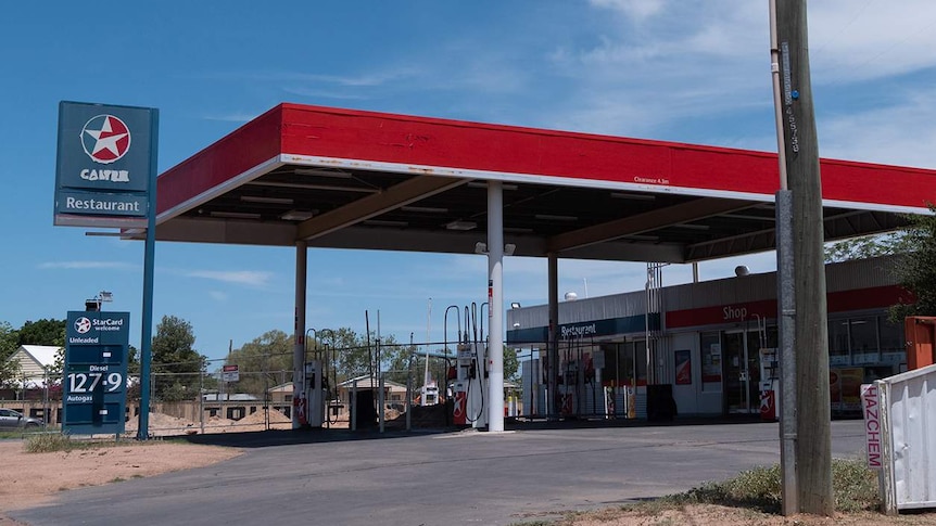 A roadhouse with fenced off bowsers sits beneath a blue sky