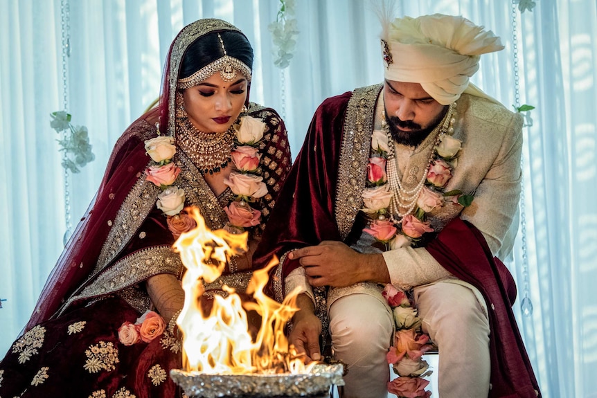 A couple sit at a fire.