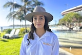 A woman with dark hair wearing a light colour Akubra hat and long sleeved white sun safe shirt.