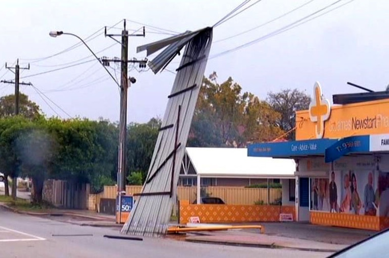 A large sheet of corrogated iron hangs from a powerline.