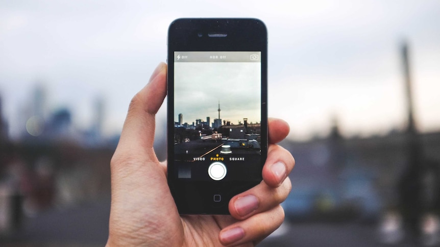 A stock image shows a person taking a photo with an iPhone.