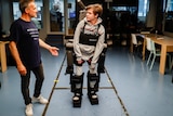 Jean-Louis Constanza stands next to his son Oscar who is standing up wearing the exoskeleton.