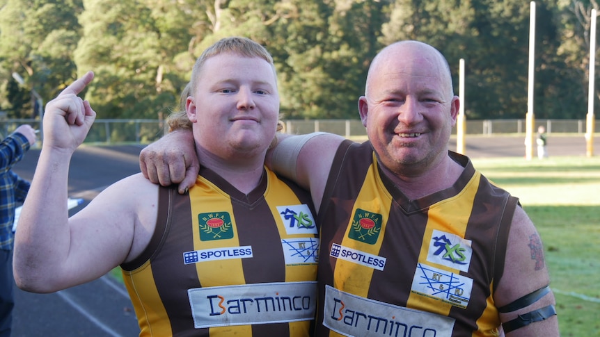 A father and son playing football together. 