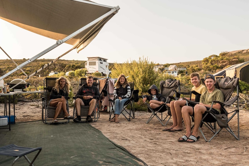 A family sitting together camping in the bush.