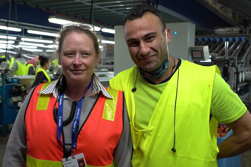 Frances MacIsaac and Morteza Darvishpoor stand together in a cherry packing shed.