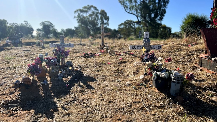 The graves of Veronica and Rusty Walker lie side by side on a sunny day in a bushland cemetery.