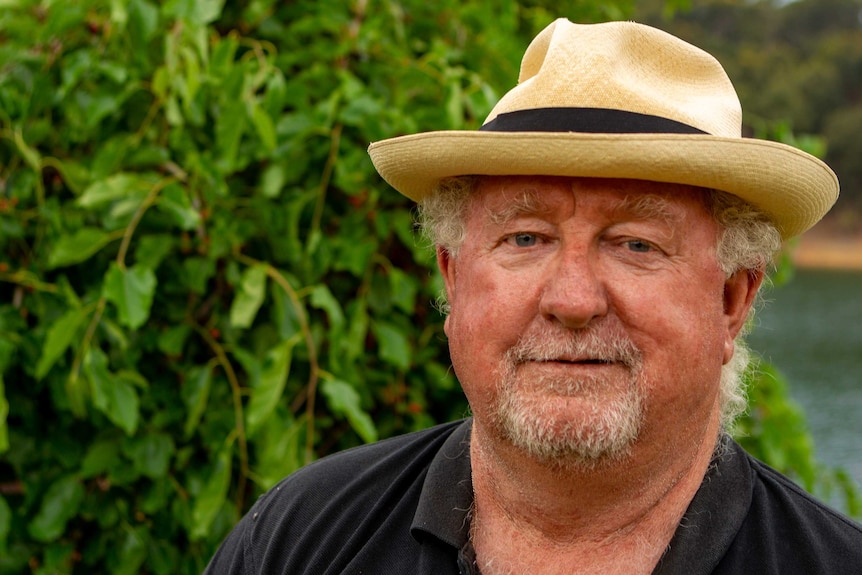 A man stands in front of a vineyard